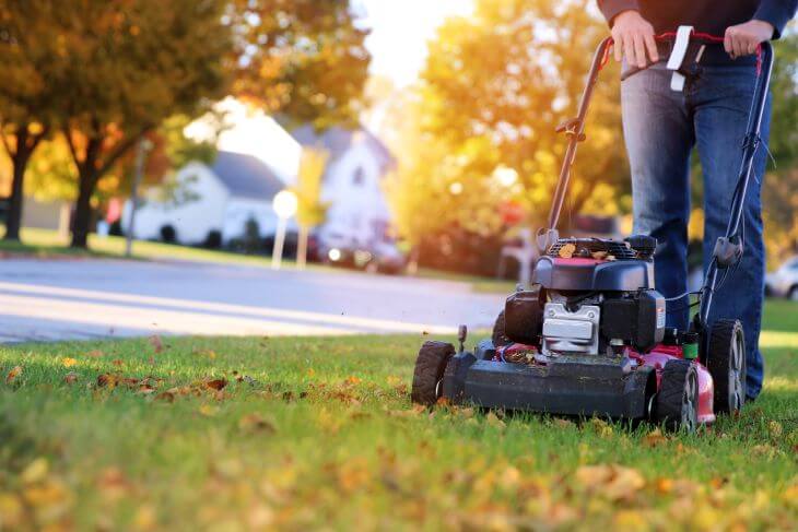 A man mowing grass of the fall lawn.