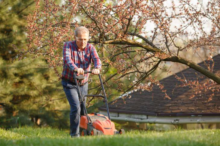 A senior man mowing the fall lawn.