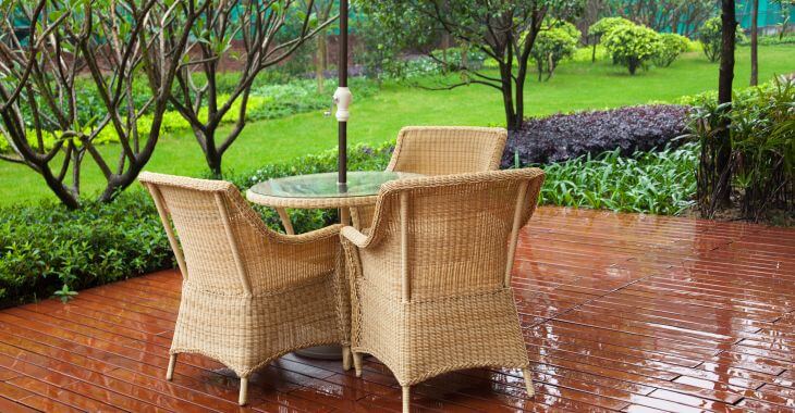 Patio with garden chairs and manicured lawn in rain.