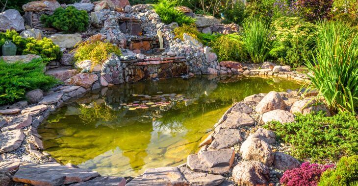 A backyard with rocky waterfall and a pond