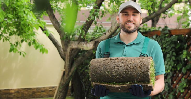 A man carrying a roll of sod.