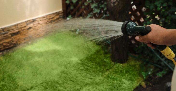 A person watering freshly laid sod.