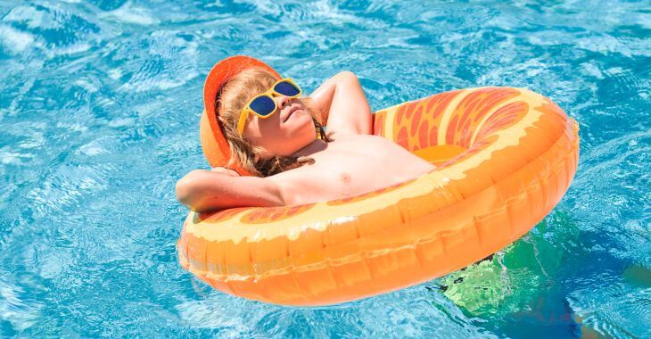 A relaxed little boy in a swim ring floating in a swimming pool