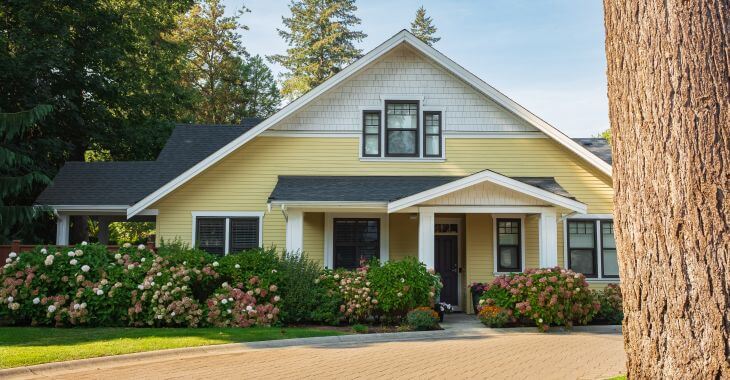 A home with landscaped and well-maintained bushes and shrubs in a front yard.