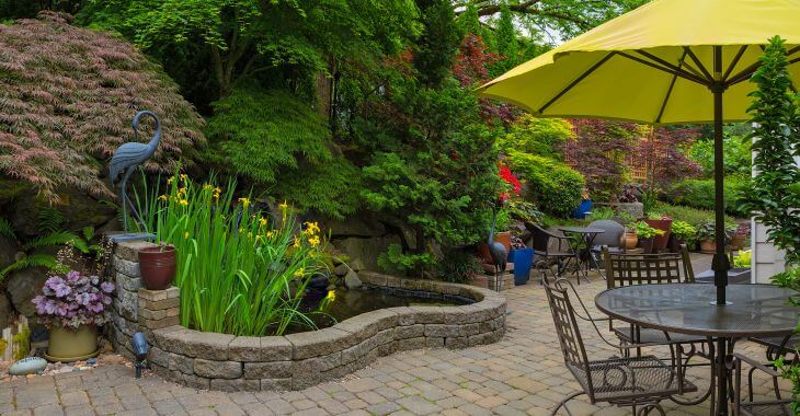 Hardscaped backyard with paver patio and a pond.