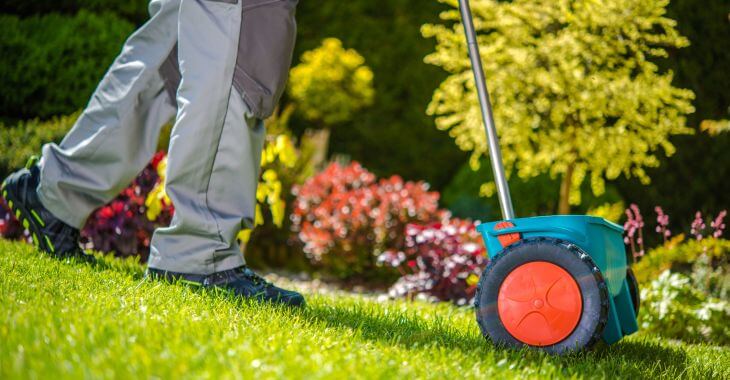 A man applying fertilizer to a lawn.