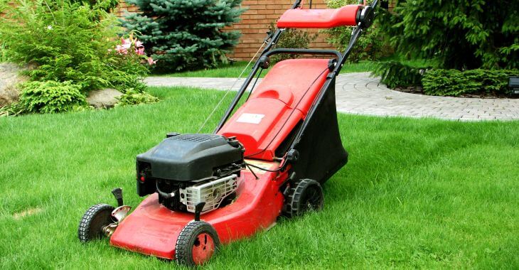 A mower on a lawn by a residential house.