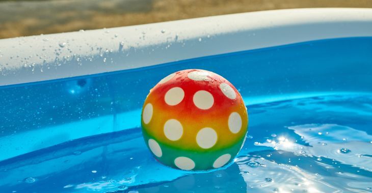 Colorful rubber ball floating in a backyard above-ground pool