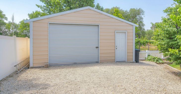 A detached garage with a gravel driveway