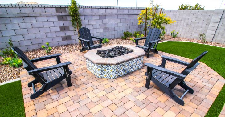 Backyard paved patio with a firepit and four garden chairs around it